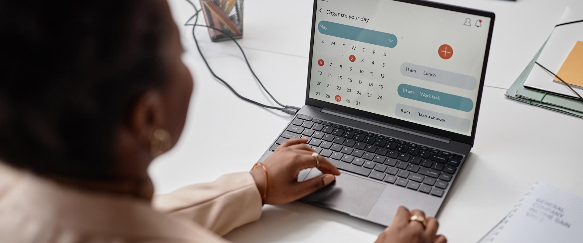 "A person uses a laptop to organize their day with a calendar app, showing tasks like lunch and work, on a tidy desk